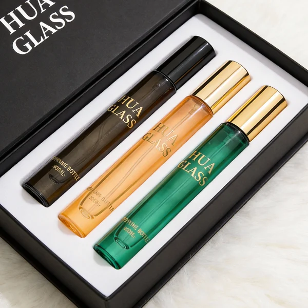 HUA0407 perfume bottle, slim cylindrical glass travel atomizer with tinted semi-transparent multi-color glass body in smoky black, orange or green featuring a subtle brand logo, topped with a luxury gold or black cylindrical zamak cap, modern minimalist travel fragrance packaging available in 10ml