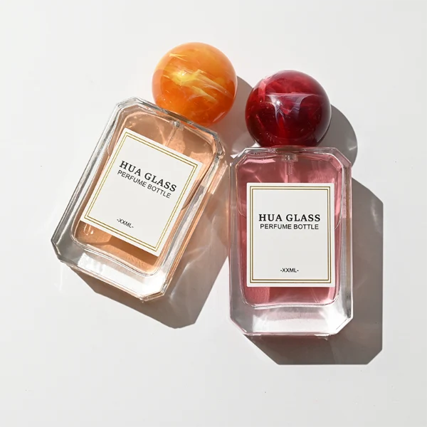 HUA0409 perfume bottle, luxury square glass bottle with beveled edges and transparent multi-color finish in orange, blue, purple, or green, featuring a rectangular paper label and a hollow round ball plastic cap with a marble pattern covering the internal sprayer, modern elegant fragrance packaging design available in 30ml, 50ml, and 100ml