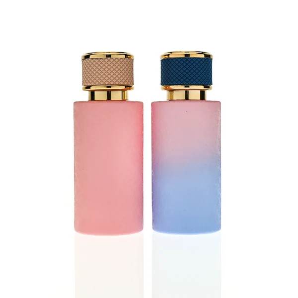 HUA0411 perfume bottle, luxury cylindrical glass bottle with glossy spray colored multi-color finish in pink or pink-blue gradient, featuring a gold-colored collar and a unique textured leather-wrapped plastic cap with gold-colored trim, modern elegant fragrance packaging design available in 30ml, 50ml, and 100ml