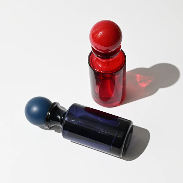 HUA0413 perfume bottle, luxury apothecary-style cylindrical glass bottle with solid opaque glossy finish in blue, green, pink, or ivory, featuring a narrow neck and a matching large round ball plastic cap, modern elegant fragrance packaging design available in 30ml, 50ml, and 100ml