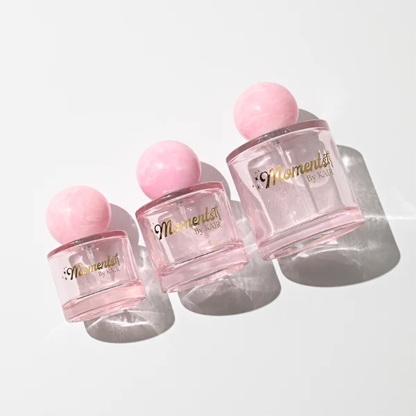 ]HUA0414 perfume bottle, luxury short cylindrical glass bottle with transparent pink finish, featuring a printed gold logo, a pink-colored collar, and a large round ball resin cap with a pink marble swirl pattern, modern elegant fragrance packaging design available in 30ml, 50ml, and 100ml