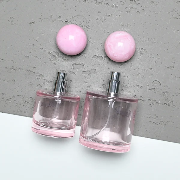 ]HUA0414 perfume bottle, luxury short cylindrical glass bottle with transparent pink finish, featuring a printed gold logo, a pink-colored collar, and a large round ball resin cap with a pink marble swirl pattern, modern elegant fragrance packaging design available in 30ml, 50ml, and 100ml