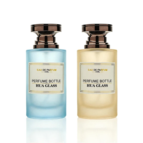 HUA0415 perfume bottle, luxury heavy-base cylindrical glass bottle with high-transparency finish showing colored liquid, featuring a gold-bordered square paper label and a unique layered hourglass-shaped plastic cap, modern elegant fragrance packaging design available in 30ml, 50ml, and 100ml