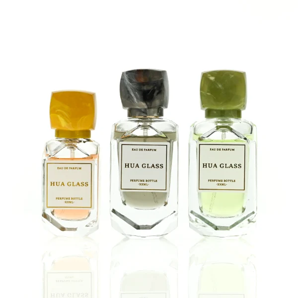 HUA0416 perfume bottle, luxury square glass bottle with a pentagonal faceted geometric shape and high-transparency finish showing colored liquid, featuring a bordered square paper label and a unique faceted square block resin cap with a marble swirl pattern, modern elegant fragrance packaging design available in 30ml and 50ml