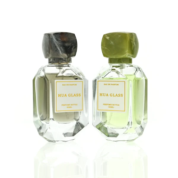 HUA0416 perfume bottle, luxury square glass bottle with a pentagonal faceted geometric shape and high-transparency finish showing colored liquid, featuring a bordered square paper label and a unique faceted square block resin cap with a marble swirl pattern, modern elegant fragrance packaging design available in 30ml and 50ml