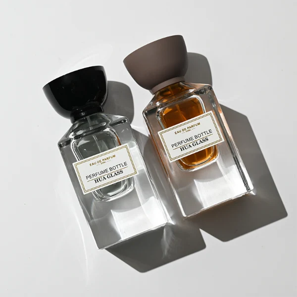HUA0417 perfume bottle, luxury square glass bottle with a heavy base and high-transparency finish showing colored liquid, featuring a gold-bordered square paper label and a unique tapered cup-shaped plastic cap in glossy black or matte brown, modern elegant fragrance packaging design available in 30ml and 50ml