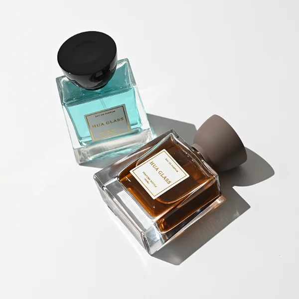 HUA0418 perfume bottle, luxury trapezoidal square glass bottle with a frosted matte multi-color finish in green, pink, blue, or yellow, featuring a bordered square paper label and a unique glossy black tapered cup-shaped plastic cap, modern elegant fragrance packaging design available in 30ml, 50ml, and 100ml