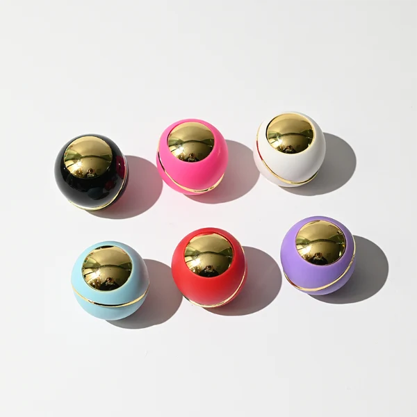 HUA0419 perfume bottle, luxury heavy-base cylindrical glass bottle with high-transparency finish showing colored liquid, featuring a gold-bordered square paper label and a unique round ball plastic cap with a diagonal gold-colored accent stripe, modern elegant fragrance packaging design available in 30ml, 50ml, and 100ml
