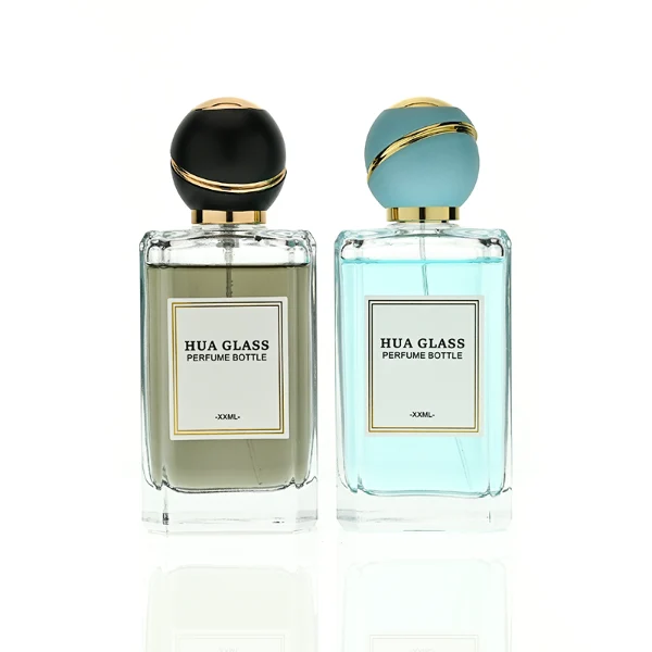 HUA0426 perfume bottle, luxury heavy-base rectangular square glass bottle with high-transparency finish showing colored liquid, featuring a gold-bordered square paper label and a unique round ball plastic cap with a diagonal gold-colored accent stripe, modern elegant fragrance packaging design available in 30ml, 50ml, and 100ml
