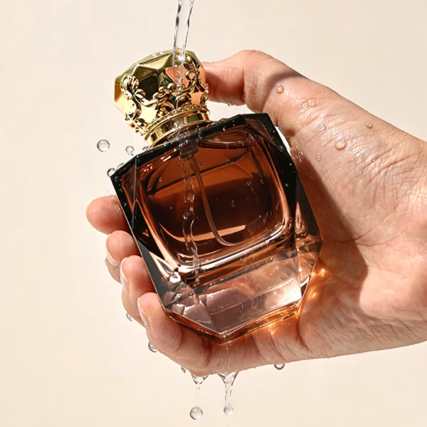 HUA0428 perfume bottle, luxury heavy-base multi-faceted angular square glass bottle with high-transparency finish showing colored liquid, featuring a matching gold-colored neck collar and an ornate crown-style zamak cap with a high-shine gold finish, premium regal fragrance packaging design available in 30ml, 50ml, and 100ml
