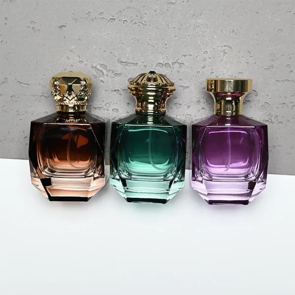 HUA0428 perfume bottle, luxury heavy-base multi-faceted angular square glass bottle with high-transparency finish showing colored liquid, featuring a matching gold-colored neck collar and an ornate crown-style zamak cap with a high-shine gold finish, premium regal fragrance packaging design available in 30ml, 50ml, and 100ml