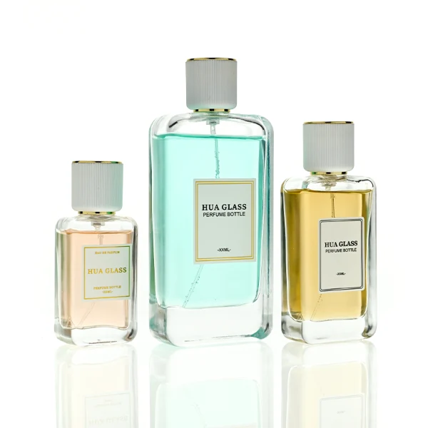 HUA0431 perfume bottle, luxury heavy-base flat rectangular glass bottle with high-transparency finish showing colored liquid, featuring a bordered square paper label and a minimalist white cylindrical plastic cap with gold-colored trim, modern elegant fragrance packaging design available in 30ml, 50ml, and 100ml