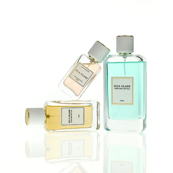 HUA0431 perfume bottle, luxury heavy-base flat rectangular glass bottle with high-transparency finish showing colored liquid, featuring a bordered square paper label and a minimalist white cylindrical plastic cap with gold-colored trim, modern elegant fragrance packaging design available in 30ml, 50ml, and 100ml