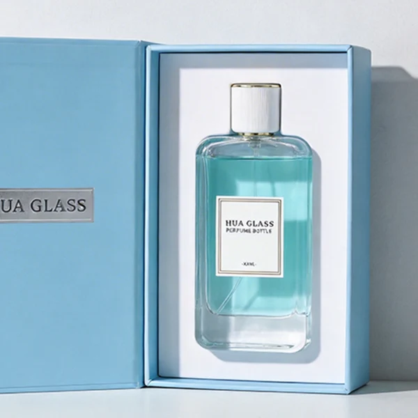 HUA0431 perfume bottle, luxury heavy-base flat rectangular glass bottle with high-transparency finish showing colored liquid, featuring a bordered square paper label and a minimalist white cylindrical plastic cap with gold-colored trim, modern elegant fragrance packaging design available in 30ml, 50ml, and 100ml