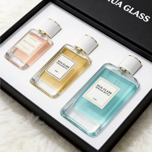 HUA0431 perfume bottle, luxury heavy-base flat rectangular glass bottle with high-transparency finish showing colored liquid, featuring a bordered square paper label and a minimalist white cylindrical plastic cap with gold-colored trim, modern elegant fragrance packaging design available in 30ml, 50ml, and 100ml