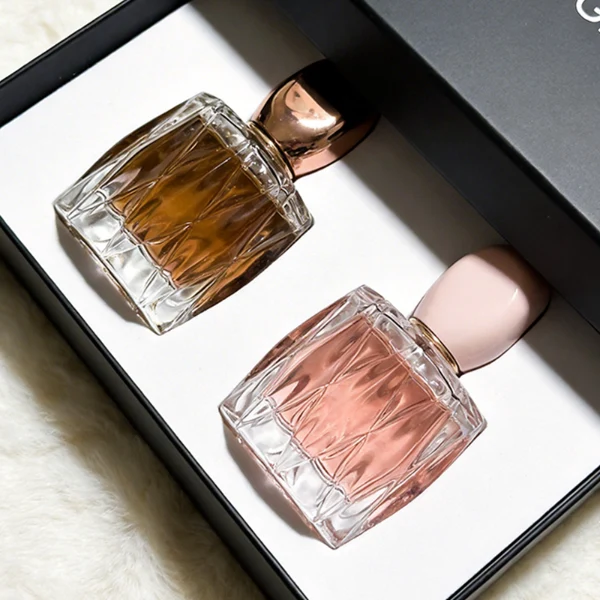 HUA0432 perfume bottle, luxury heavy-base rounded square glass bottle with wavy sculpted embossed patterns and high-transparency clear finish, featuring a unique irregular pebble-shaped plastic cap with a mirror-shine glossy rose gold finish, modern elegant fragrance packaging design