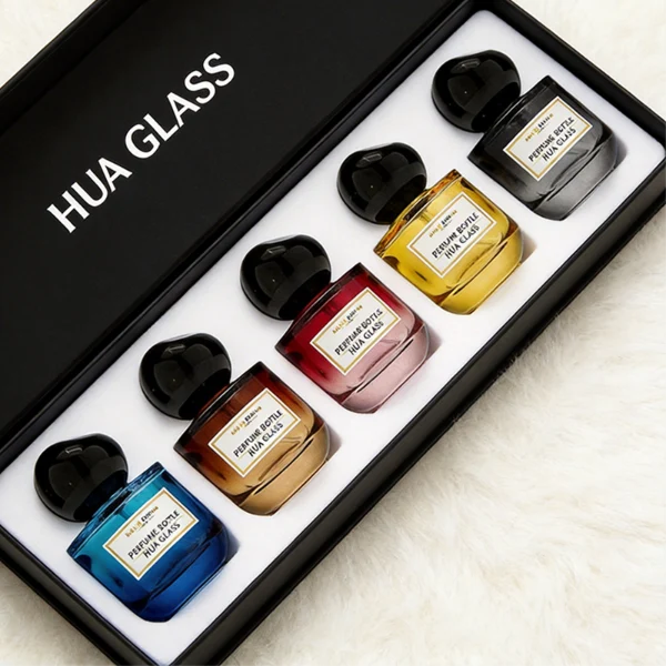 HUA0433 perfume bottle, luxury heavy-base round cylindrical glass bottle with translucent deep multi-color finish, featuring a bordered square paper label and a unique irregular pebble-shaped plastic cap in a glossy black finish, modern artistic fragrance packaging design available in 50ml and 100ml