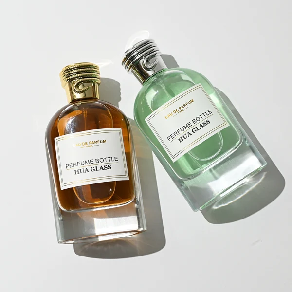 HUA0434 perfume bottle, luxury 100ml heavy-base round cylindrical glass bottle with high-transparency clear finish, featuring a bordered square paper label and a unique horizontal threaded cylindrical plastic cap with a mirror-shine metallic chrome finish, modern elegant fragrance packaging design