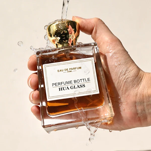 HUA0441 perfume bottle, luxury heavy-base trapezoidal glass bottle with high-transparency clear finish, featuring a bordered square paper label and a flared hourglass solid Zamak cap with a mirror-shine glossy finish, modern elegant fragrance packaging design available in 30ml, 50ml, and 100ml