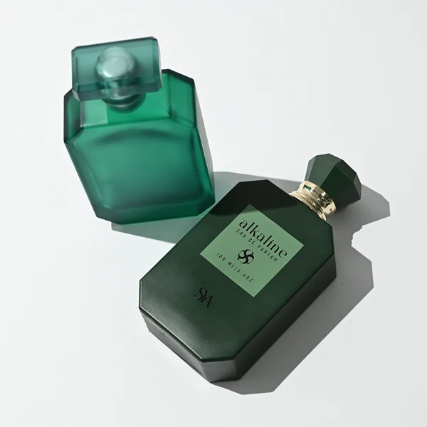 HUA0443 perfume bottle showcases a square angular glass body in vibrant frosted, solid, and gradient color options. It is crowned with artistic plastic caps featuring crown, cube, and diamond-cut shapes. Designed for wholesalers, it provides 30ml, 50ml, and 100ml choices, combining aesthetic variety with durable design for diverse fragrance lines.