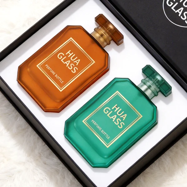 HUA0443 perfume bottle showcases a square angular glass body in vibrant frosted, solid, and gradient color options. It is crowned with artistic plastic caps featuring crown, cube, and diamond-cut shapes. Designed for wholesalers, it provides 30ml, 50ml, and 100ml choices, combining aesthetic variety with durable design for diverse fragrance lines.