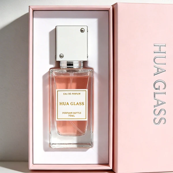 Two tall rectangular clear glass perfume bottles stand side by side, filled with light pink and grey-green liquids. Both feature a white square label and are topped with tall cube caps accented by tiny corner rhinestones—presented in white with a silver collar on the left, and black with a gold collar on the right.