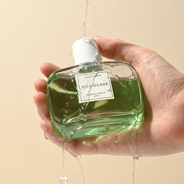 HUA0446 perfume bottle features a clear rounded and short rectangular glass body paired with a sleek cylindrical black or white plastic cap. Designed for wholesalers, it offers a 50ml capacity option, combining a modern minimalist style with durable functionality for diverse cosmetic fragrance lines.