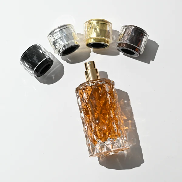 HUA0448 perfume bottle features a textured, diamond-patterned clear glass body paired with a matching cylindrical faceted plastic cap in black, silver, or gold. Designed for wholesalers, it offers 50ml and 100ml options, combining an elegant geometric design with practical durability for premium fragrance lines.
