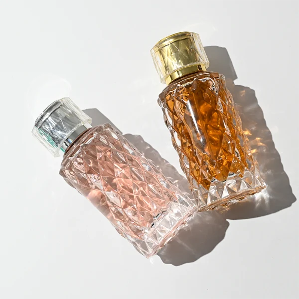 HUA0448 perfume bottle features a textured, diamond-patterned clear glass body paired with a matching cylindrical faceted plastic cap in black, silver, or gold. Designed for wholesalers, it offers 50ml and 100ml options, combining an elegant geometric design with practical durability for premium fragrance lines.
