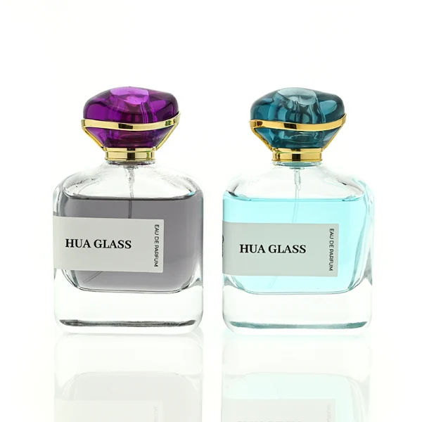 HUA0449 perfume bottle features a rounded short, thick-bottom square clear glass body paired with a unique organic, abstract-shaped translucent cap with a gold collar. Designed for wholesalers, it offers a 100ml capacity option, blending a modern minimalist profile with structural durability for distinct fragrance collections.