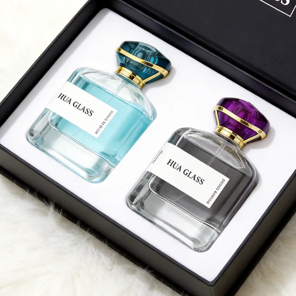HUA0449 perfume bottle features a rounded short, thick-bottom square clear glass body paired with a unique organic, abstract-shaped translucent cap with a gold collar. Designed for wholesalers, it offers a 100ml capacity option, blending a modern minimalist profile with structural durability for distinct fragrance collections.