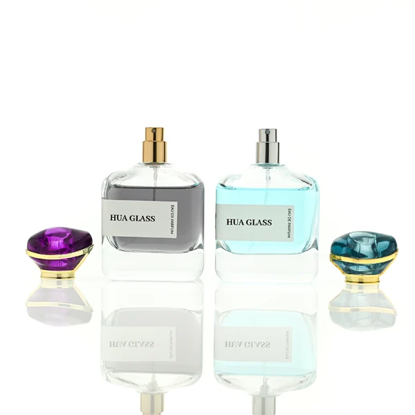 HUA0449 perfume bottle features a rounded short, thick-bottom square clear glass body paired with a unique organic, abstract-shaped translucent cap with a gold collar. Designed for wholesalers, it offers a 100ml capacity option, blending a modern minimalist profile with structural durability for distinct fragrance collections.