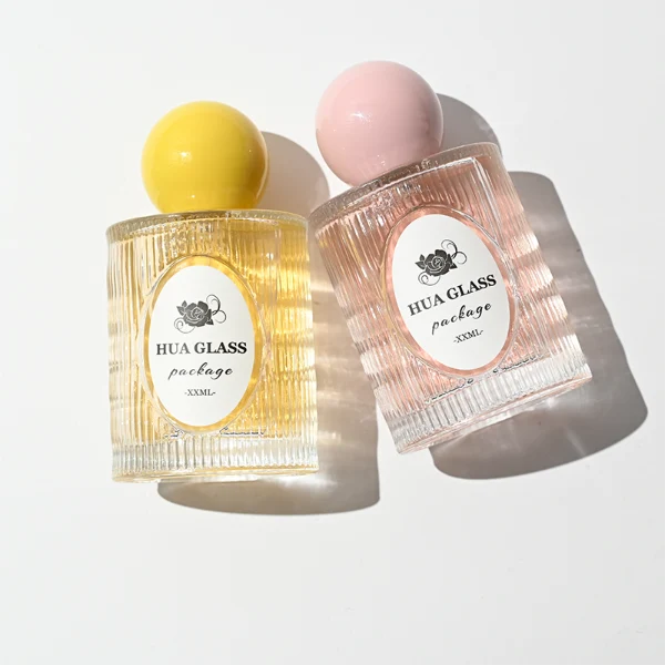 HUA0450 perfume bottle features a clear cylindrical glass body with vertical ribbed grooves, paired with a smooth spherical ball-shaped plastic cap in purple, pink, or yellow. Designed for wholesalers, it offers a 50ml capacity option, combining an elegant textured profile with structural durability for distinct fragrance lines.