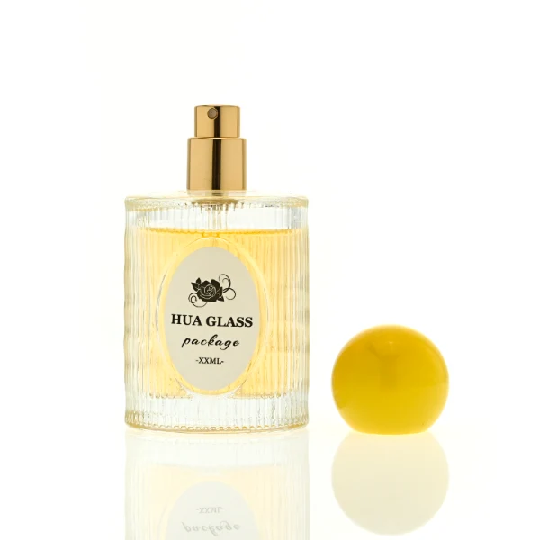HUA0450 perfume bottle features a clear cylindrical glass body with vertical ribbed grooves, paired with a smooth spherical ball-shaped plastic cap in purple, pink, or yellow. Designed for wholesalers, it offers a 50ml capacity option, combining an elegant textured profile with structural durability for distinct fragrance lines.