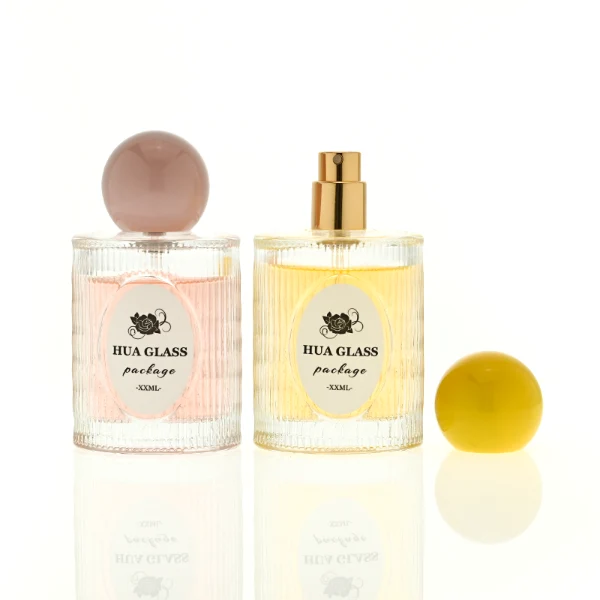 HUA0450 perfume bottle features a clear cylindrical glass body with vertical ribbed grooves, paired with a smooth spherical ball-shaped plastic cap in purple, pink, or yellow. Designed for wholesalers, it offers a 50ml capacity option, combining an elegant textured profile with structural durability for distinct fragrance lines.