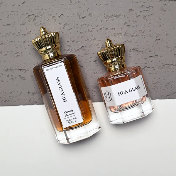 HUA0451 perfume bottle features a clear hexagonal glass body paired with an ornate crown-shaped plastic cap in gold or silver. Designed for wholesalers, it offers 50ml and 100ml choices, combining a regal aesthetic with structural durability for diverse fragrance lines.