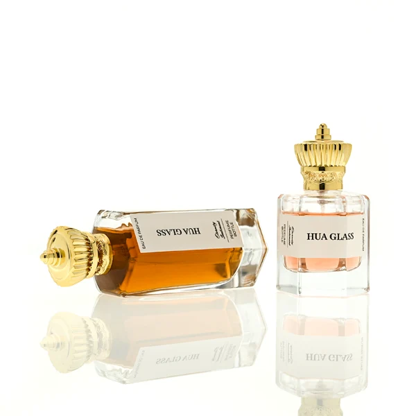 HUA0451 perfume bottle features a clear hexagonal glass body paired with an ornate crown-shaped plastic cap in gold or silver. Designed for wholesalers, it offers 50ml and 100ml choices, combining a regal aesthetic with structural durability for diverse fragrance lines.