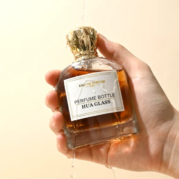 HUA0456 perfume bottle features a rounded, curved clear glass body paired with a unique crown-like glossy golden plastic cap. Designed for wholesalers, it offers 50ml and 100ml capacity options, combining an elegant silhouette with practical durability.