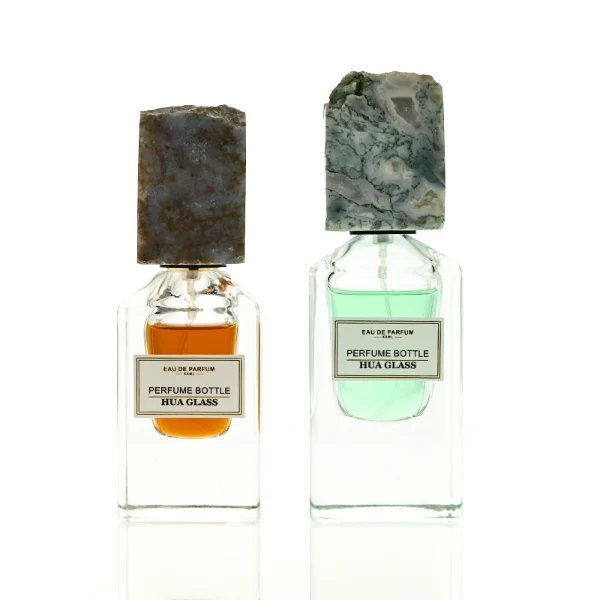 HUA0457 perfume bottle showcases a clear, thick-bottomed rectangular glass frame paired with a striking, unique block cap made of raw natural stone. Designed for premium wholesale markets, it offers 30ml and 50ml options, combining an organic elemental style with architectural structural durability.