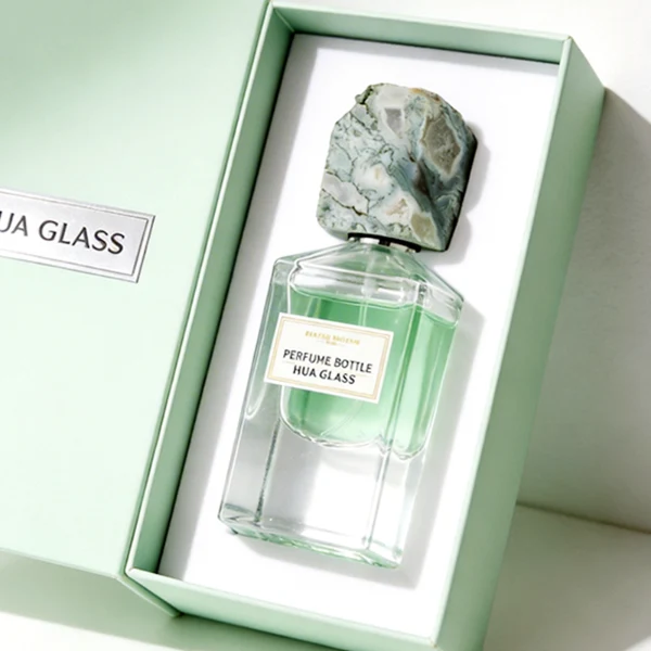 HUA0457 perfume bottle showcases a clear, thick-bottomed rectangular glass frame paired with a striking, unique block cap made of raw natural stone. Designed for premium wholesale markets, it offers 30ml and 50ml options, combining an organic elemental style with architectural structural durability.