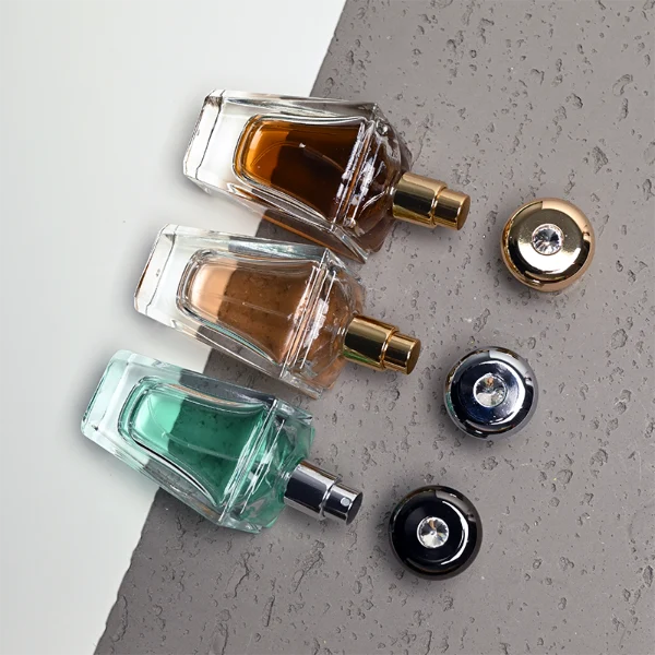 HUA0459 perfume bottle, features an architectural, angular clear glass body with a tapered silhouette, paired with a heavy metallic crown-shaped Zamac cap. Designed for luxury wholesalers, it offers a 50ml capacity option blending upscale geometric lines with premium durability.
