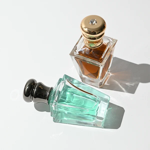 HUA0459 perfume bottle, features an architectural, angular clear glass body with a tapered silhouette, paired with a heavy metallic crown-shaped Zamac cap. Designed for luxury wholesalers, it offers a 50ml capacity option blending upscale geometric lines with premium durability.