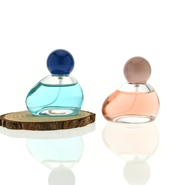 HUA0460 perfume bottle features an asymmetrical, organic pebble-shaped clear glass body paired with a glossy spherical ball cap in blue, red, or pink, it offers a 50ml capacity option, blending a playful geometric profile with high wholesale utility.