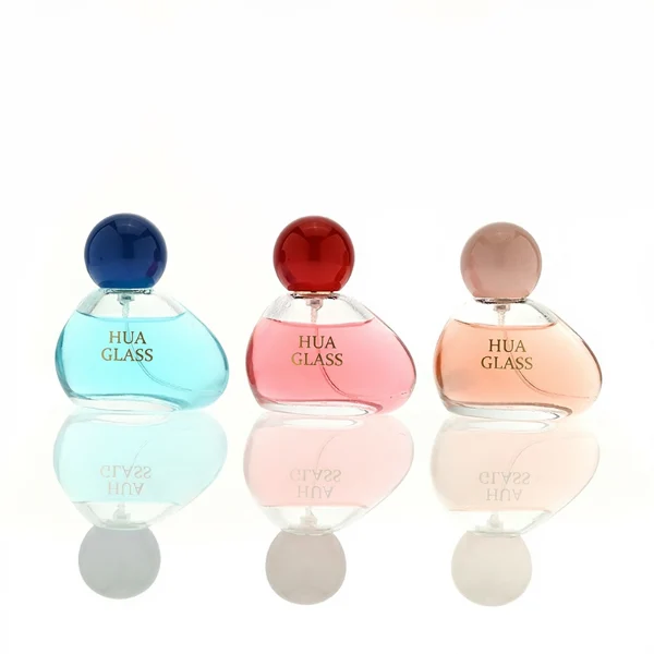 HUA0460 perfume bottle features an asymmetrical, organic pebble-shaped clear glass body paired with a glossy spherical ball cap in blue, red, or pink, it offers a 50ml capacity option, blending a playful geometric profile with high wholesale utility.