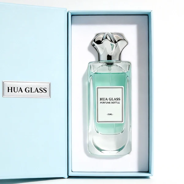 A luxury rectangular perfume bottle featuring a thick, rounded clear glass base and a heavy metallic crown-shaped Zamac cap in gold, silver, or black.