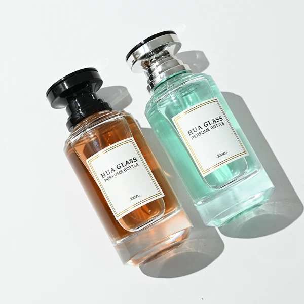 A thick-bottomed cylindrical glass perfume bottle featuring a round, curved profile with gradient color finish choices like black, blue, pink, or brown, topped with a uniquely styled injection-molded plastic cap in black or white.
