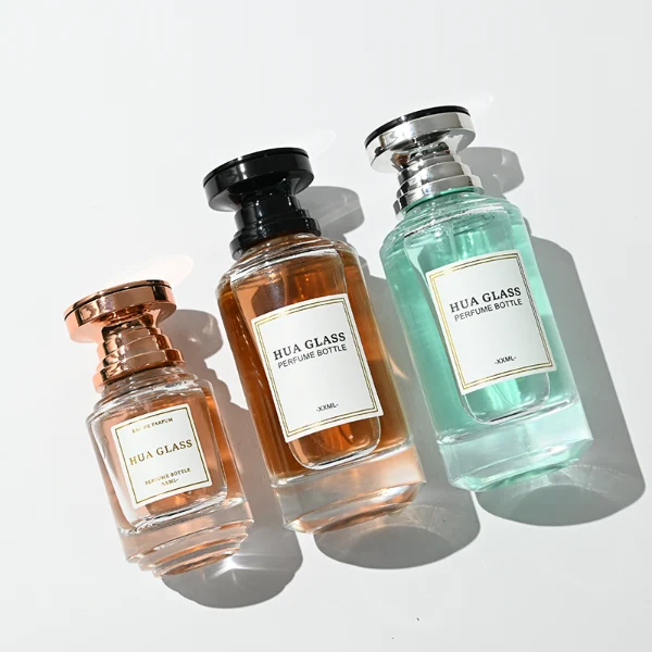 A thick-bottomed cylindrical glass perfume bottle featuring a round, curved profile with gradient color finish choices like black, blue, pink, or brown, topped with a uniquely styled injection-molded plastic cap in black or white.