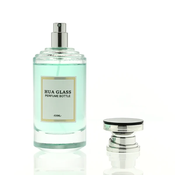 A thick-bottomed cylindrical glass perfume bottle featuring a round, curved profile with gradient color finish choices like black, blue, pink, or brown, topped with a uniquely styled injection-molded plastic cap in black or white.