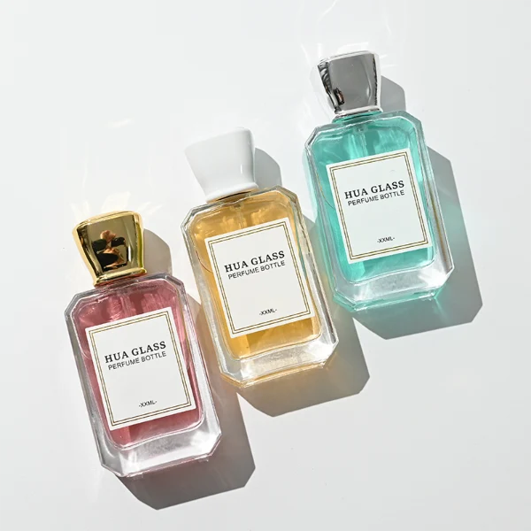 A diamond-cut rectangular glass perfume bottle with a clear, angular profile and an elegant faceted border, paired with a smooth, trapezoidal square plastic cap available in gold, silver, or matte white.