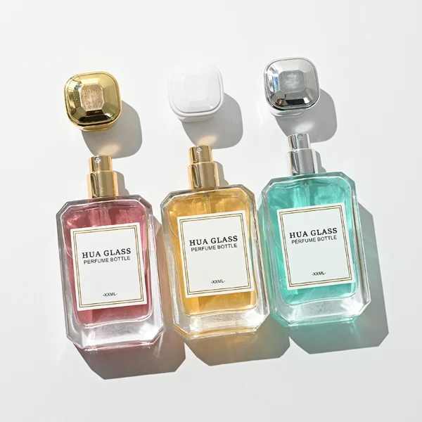 A diamond-cut rectangular glass perfume bottle with a clear, angular profile and an elegant faceted border, paired with a smooth, trapezoidal square plastic cap available in gold, silver, or matte white.